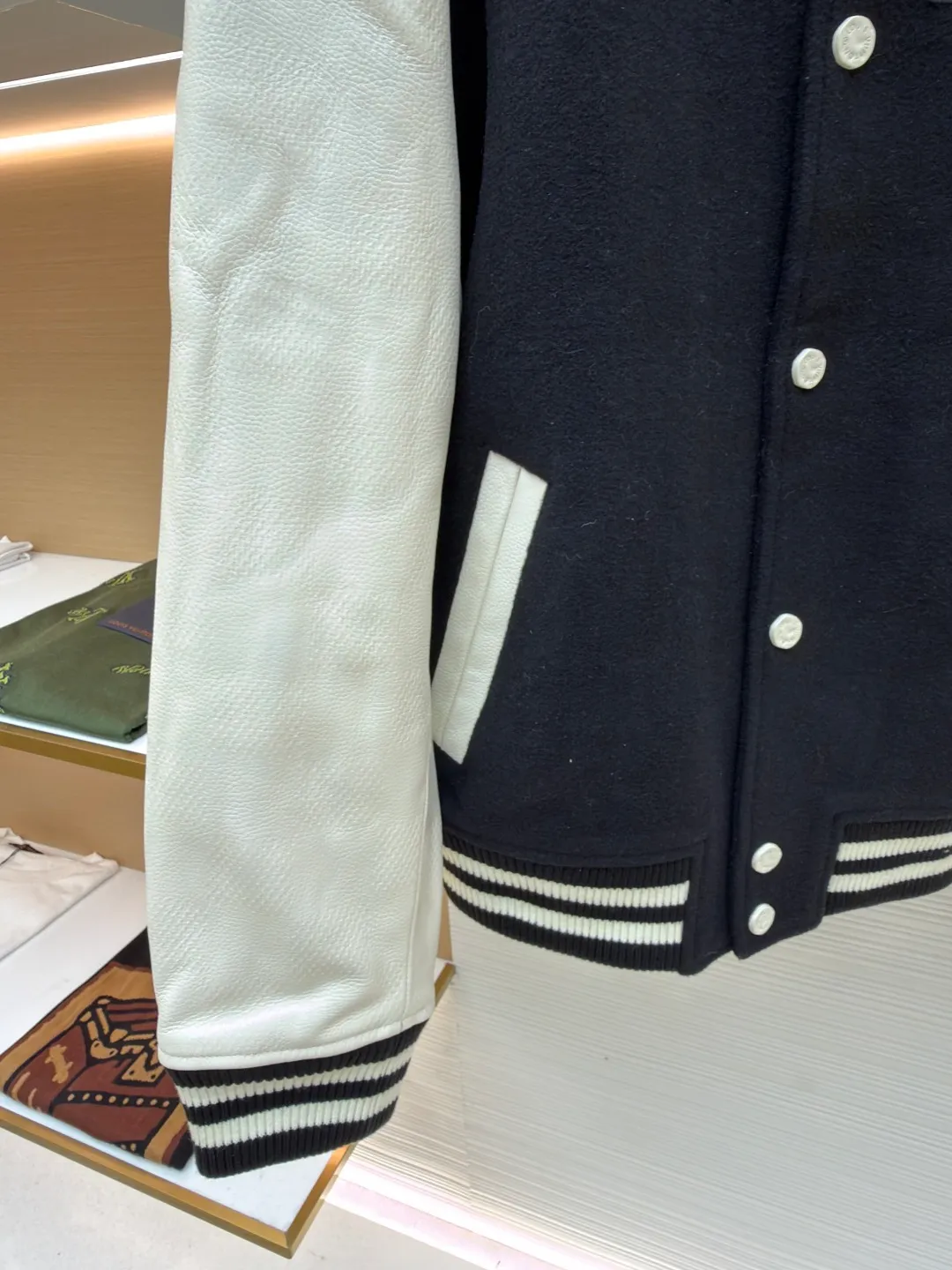 LOUIS VUITTON checkerboard embossed genuine leather and wool baseball jersey ●Original version: 51000 purchased and developed ●Item number: 1680926-i15 ●Fabric: genuine leather wool fabric ●Technology: embroidery ●Version: fitted version ●Weight: about 1770 grams ●Size: 44-46-48-50 ●Description: The fabric is made of 80% wool, with a weight of 750g. It is made of newly sheared wool and is dyed in reactive black in the vat. The colored cloth is bristle process. After brushing 5 times and washing 6 times, the fluffy surface fluff is trimmed flat, and the surface of the fabric appears fluffy. It has a hollow three-dimensional fluffy effect. You can feel the elasticity of the fabric when you touch and press it with your hands. The newly sheared wool yarn is long-fiber and is not easy to pill after shearing. The front and back panels are embroidered with Tajima embroidery machines imported from Japan. The nylon material is super matte and the tatami stitch method is multi-layered. Overlapping thread embroidery, the front chapter is made of viscose yarn, three-dimensional toothbrush embroidery, the mold is opened to determine the pile height and the suede is smoothed by hand, using acrylic round bubble beads, the surface of the bubble beads is sprayed three times, the base paint is latex paint, and the middle layer is sprayed with pearls Pearl white paint, the outer layer is sprayed with translucent glossy paint, the translucent bright white effect is completely comparable to that of mother-of-pearl. There are a total of 154 beads in the chapter. Each bead is dusted and positioned to ensure that it is flush with the edge of the chapter. The visual effect is not obtrusive. The two sleeves are made of water Made of dyed cowhide. Compared with spray-painted cowhide, there is nothing attached to the surface of water-dyed cowhide. Pure water-based dyes are continuously stirred in the tank to naturally color. During the period, samples are taken to compare the color of the Y-version sleeves according to the degree of coloring. When the colors are basically the same, they can be washed and dried naturally to produce the finished product. The thickness of the finished leather is 12mm. The embossing is made of a large-size aviation aluminum plate material mold. All the flowers are pressed according to the code positioning. An electric hydraulic control system is used, and the constant temperature and timing are automatically operated. The small sleeve logo is embossed separately from the small mold. It is pressed by electromagnetic pulse pressure and heating. After the sleeves are cut and embossed, the leather base is all shoveled to a thickness of 8mm. The leather thickness is reduced and the hand feels softer and closer to the body. The diamond-shaped plaid embossing on the surface causes an anti-skin phenomenon due to the thinning of the leather base. The pattern will naturally increase from the deep base state. Lightened, the diamond check pattern and the leather pebbles form a visually invisible effect. It is matched with cupro + cotton blended lining, the ribs are made of combed cotton yarn, and the horizontal loom imported from Taiwan has inter-color jacquard. It is matched with a custom-made molded aluminum alloy material with a logo spray-painted four-button buckle.